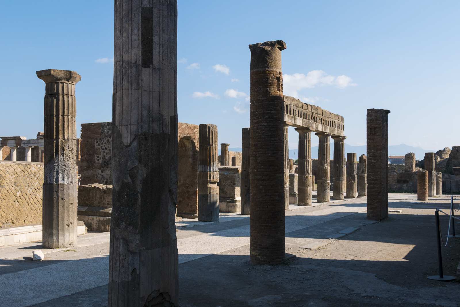 Ruines du forum de Pompéi avec des colonnes antiques sous un ciel clair.