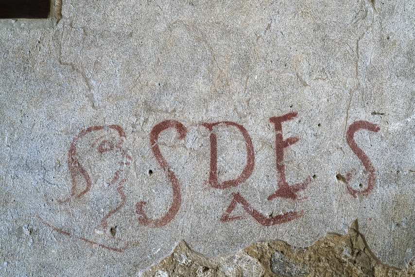 Graffito antique avec l’inscription « SDES » et un visage stylisé à l’intérieur de la Maison de Thiasos