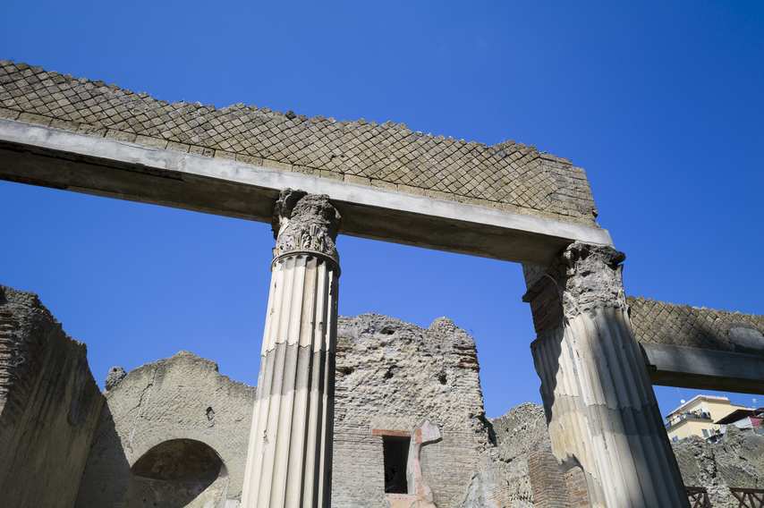 Well-preserved Corinthian columns in the ruins of Herculaneum with blue sky in the background