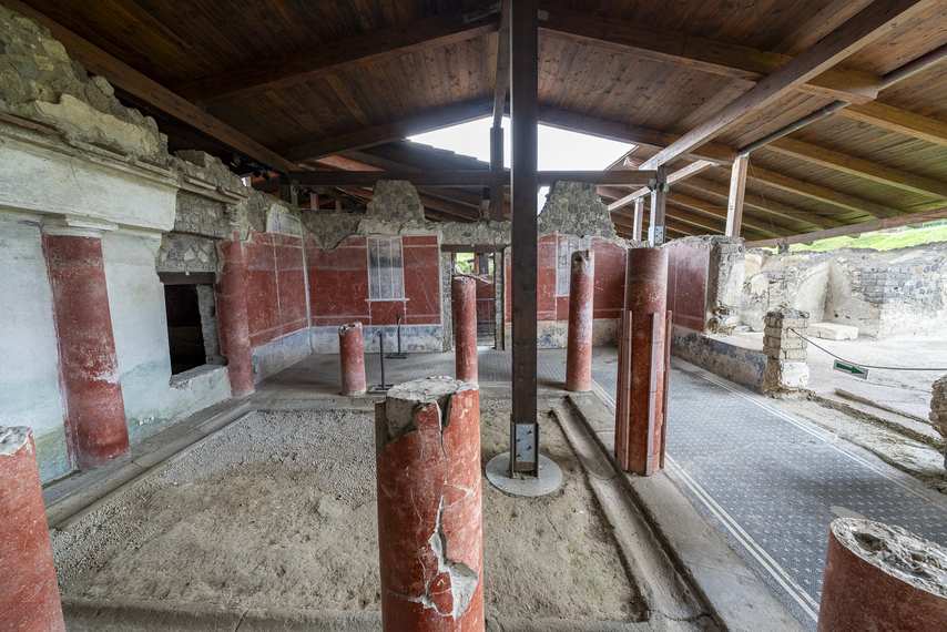 Damaged red columns in covered environment of Villa Ariadne in Stabiae