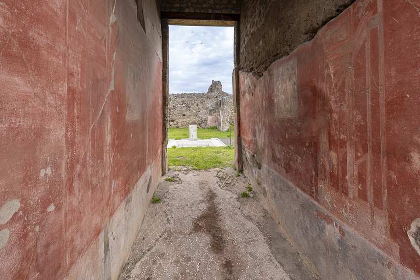 Frescoed corridor with red walls in the House of Meleager in Pompeii