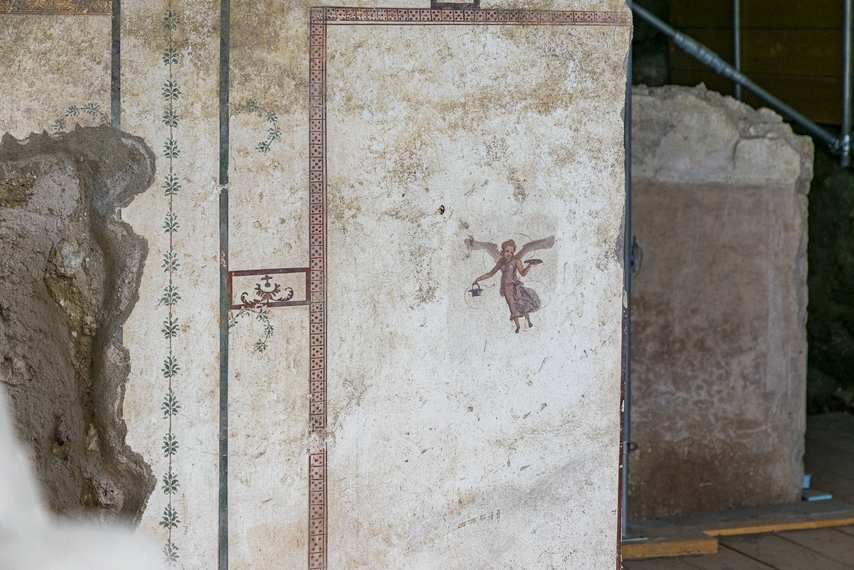 Winged putto painted on white wall in the House of Leda and the Swan in Pompeii