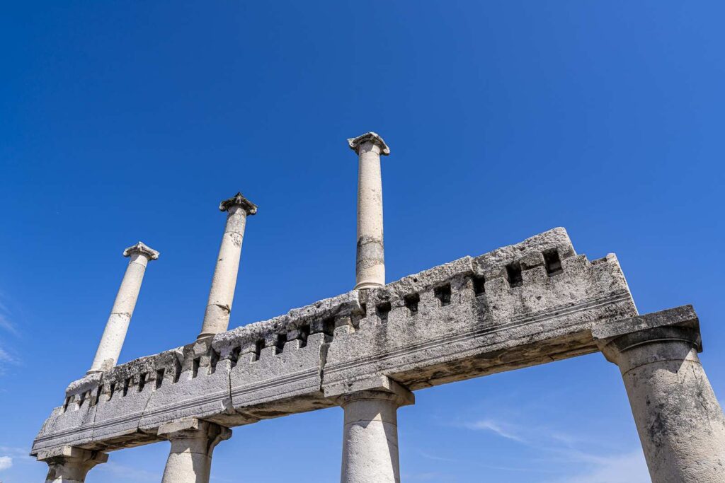 View from below the columns of the Forum of Pompeii against a deep blue sky