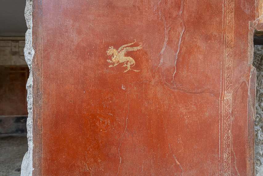 Red fresco with golden griffin in the Fullonica of Stephanus in Pompeii