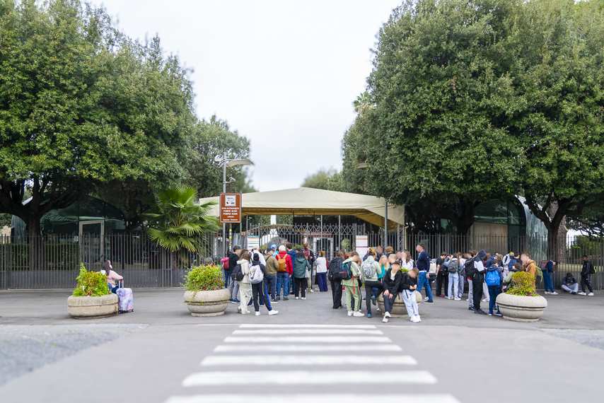 Entrance to the Amphitheater at the Pompeii Archaeological Park with line of visitors and trees in the background