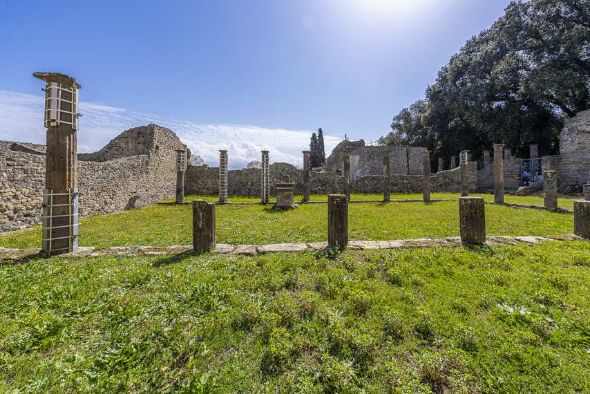 Ruins of the Triangular Forum in Pompeii with stone columns and green lawn