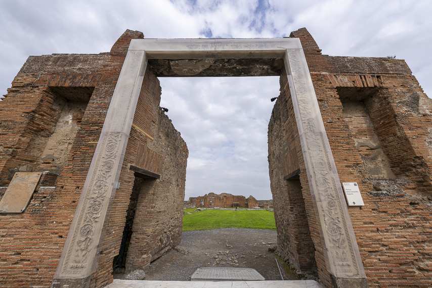 Entrance to the Portico of Concordia Augusta in Pompeii with modern arch and ancient ruins.