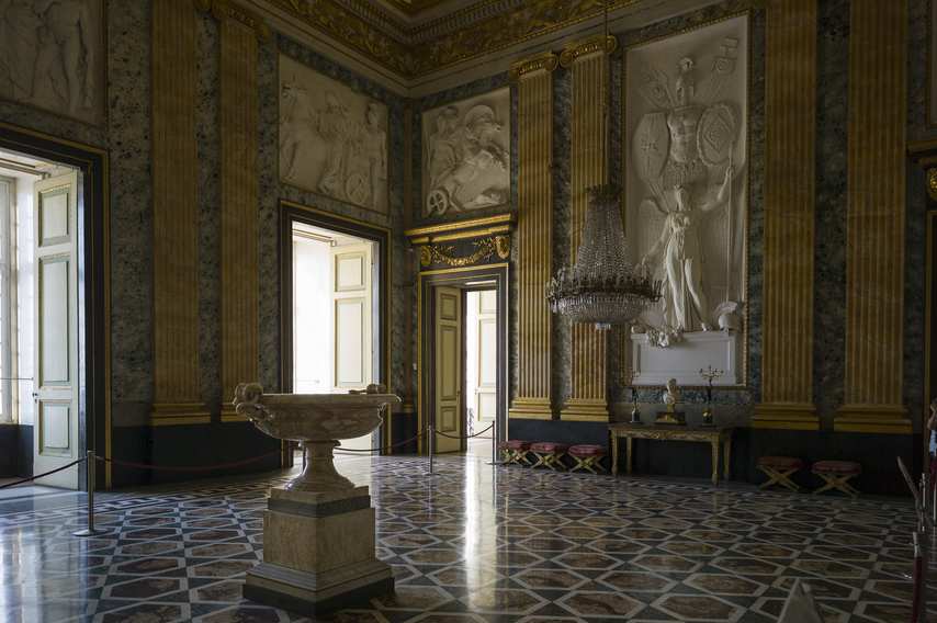 Hall of the Royal Palace of Caserta with gilded columns, bas-reliefs and crystal chandelier