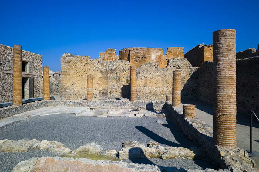 Ruins with brick columns in the House of Championnet in Pompeii under a clear sky