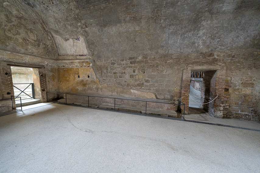 Indoor hall of the Forum Baths of Pompeii with frescoed vault and stone walls