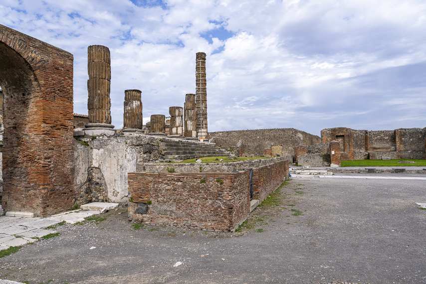 Columns of the Temple of Jupiter in Pompeii with Roman arch and Forum in the background