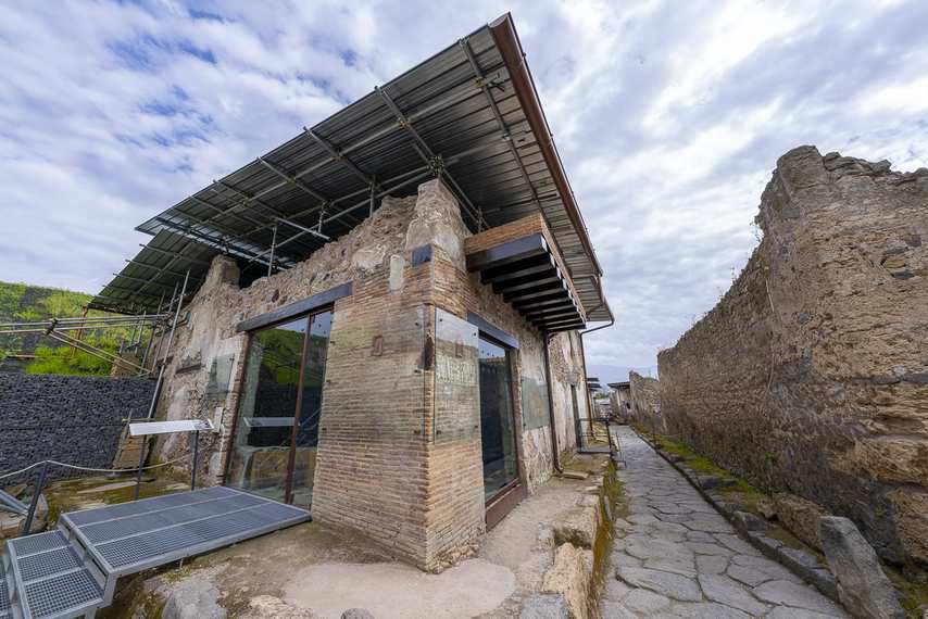 Exterior of an ancient thermopolium in Pompeii with protective roof and modern glazing